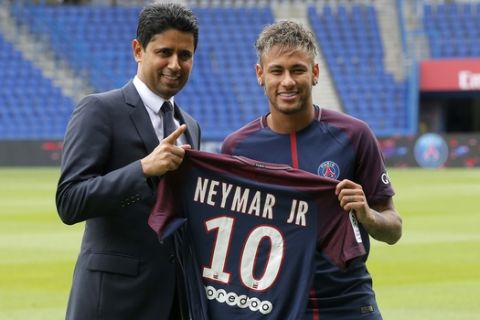 Brazilian soccer star Neymar holds his team shirt as he stands with the chairman of Paris Saint-Germain Nasser Al-Khelaifi following a press conference in Paris Friday, Aug. 4, 2017. Neymar arrived in Paris on Friday the day after he became the most expensive player in soccer history when completing his blockbuster transfer to Paris Saint-Germain from Barcelona for 222 million euros ($262 million).(AP Photo/Michel Euler)