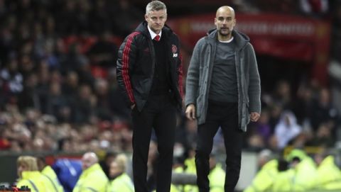 Manchester United manager Ole Gunnar Solskjaer and Manchester City coach Pep Guardiola, right, stand side by side during the English Premier League soccer match between Manchester United and Manchester City at Old Trafford Stadium in Manchester, England, Wednesday April 24, 2019. (AP Photo/Jon Super)