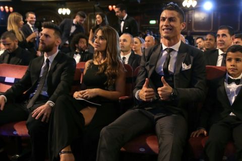 Portuguese soccer player Christiano Ronaldo, second from right, and son Cristiano Ronaldo Jr., right, sit beside Argentinian soccer player Lionel Messi, left, and wife Antonella during the The Best FIFA 2017 Awards at the Palladium Theatre in London, Monday, Oct. 23, 2017. (AP Photo/Alastair Grant)