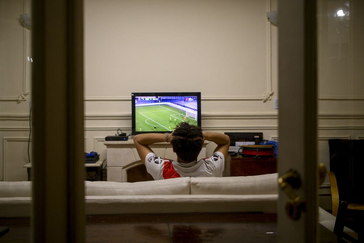 Φίλαθλος παρακολουθεί ποδόσφαιρο στην τηλεόραση, πειρατική TV
