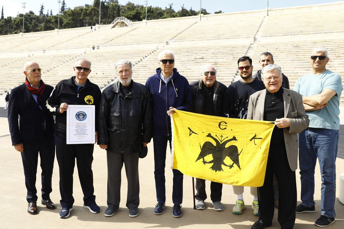 Οι παλαίμαχοι της ΑΕΚ με την σημαία της ομάδας και την πλακέτα που αναφέρει το ρεκόρ Guinness για την παρουσία 80.000 θεατών σε αγώνα μπάσκετ
